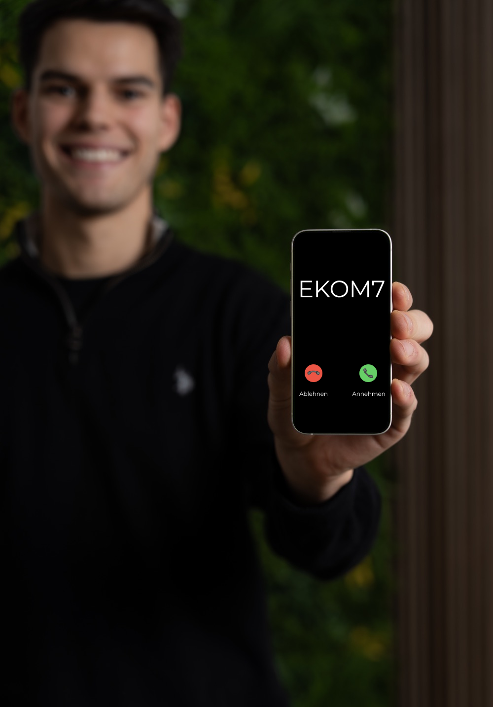 Gründer von EKOM7 Niclas Klopfer hält Handy in der Hand, während "EKOM7" anruft.